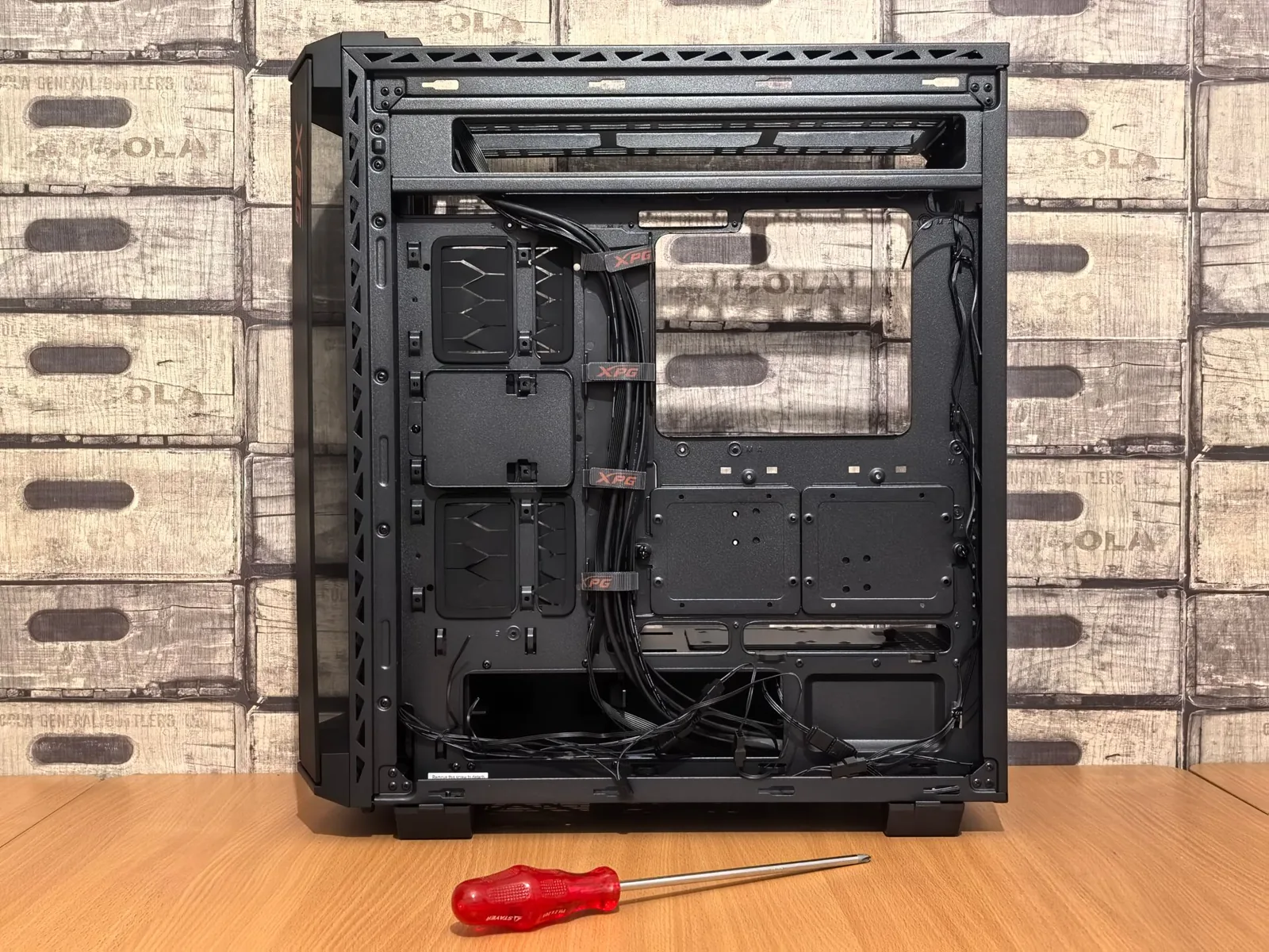 Gabinete de PC vacío con los cables organizados y un destornillador, listo para armar